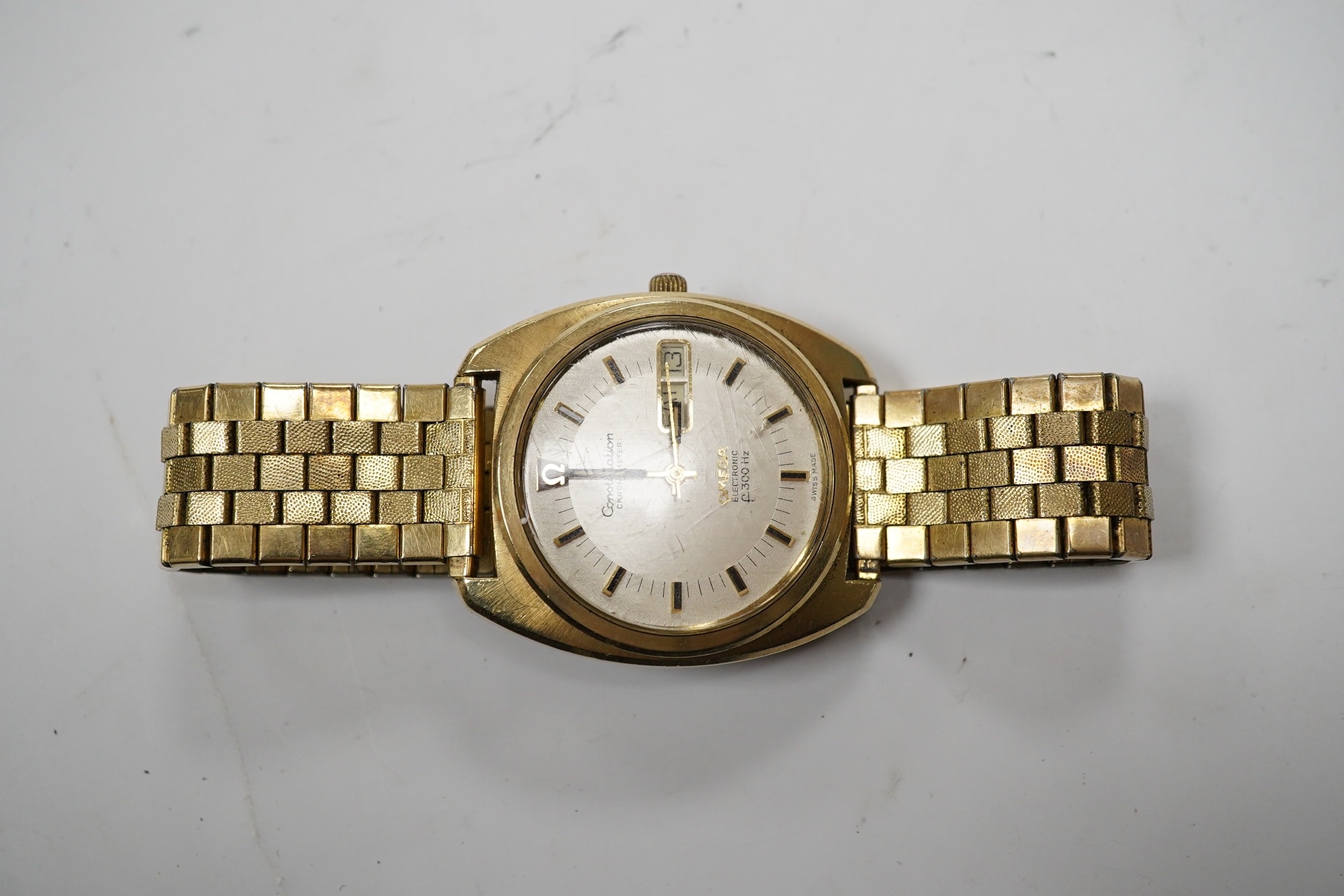 A gentleman's steel and gold plated Omega Constellation Electronic wrist watch, with baton numerals and day/date aperture, case diameter 38mm, on an associated gold plated strap. Condition - poor